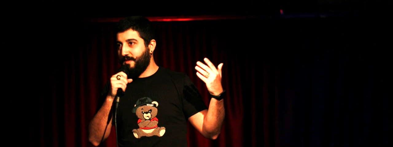 Speaking into a microphone on stage in front of a red curtain